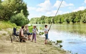 4 family members enjoying fishing and camping on bank of river
