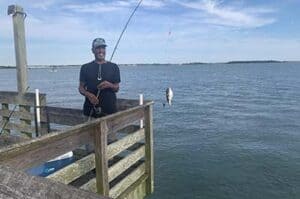 man on pier fishing caught a small fish