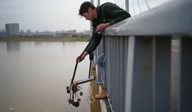 Man on bridge magnet fishing